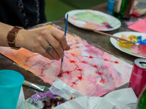Teilnehmerin malt mit Aquarellfarben auf Papier im Atelier