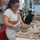 Teilnehmerin drückt Ton in eine Musterform beim Keramikworkshop im MainKreativRaum