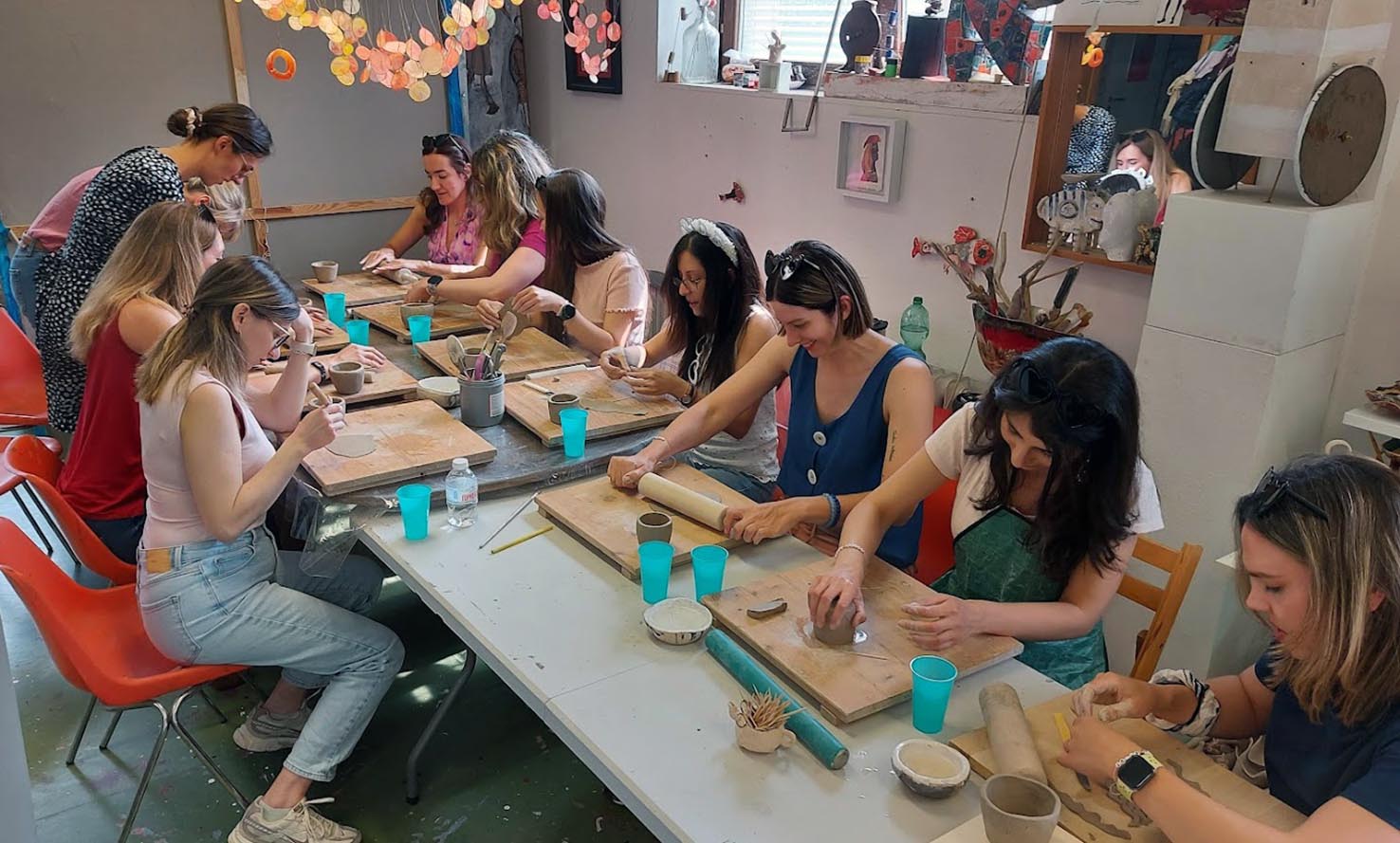 Große Gruppe formt gemeinsam Ton an einem langen Tisch beim Junggesellinnenabschied im MainKreativRaum